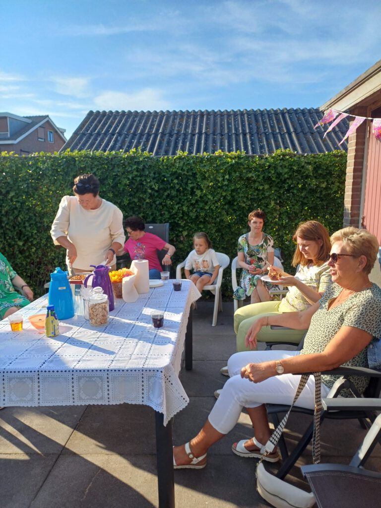 Personen aan een tafel in de tuin bij een feestelijke bijeenkomst